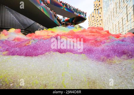 London, UK. 03rd Aug, 2022. People interact with 'Island of Foam: Version XVIII', a colourful, constantly changing foam installation. The installation is a UK premiere from German artist Stephanie Lüning (who is operating the 'foam cannon' at the top of the stairs), transforming Greenwich Peninsula with mountains of rainbow coloured foam. Credit: Imageplotter/Alamy Live News Stock Photo