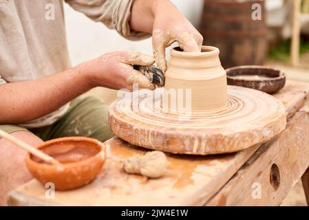 male master in light linen shirt craftsman sculpts jug or vase from clay Stock Photo