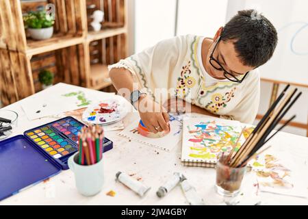 Young hispanic woman painting clay ceramic at art studio Stock Photo