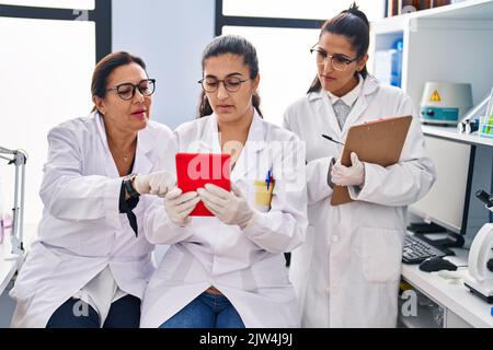 Three woman scientists using touchpad write on checklist at laboratory Stock Photo
