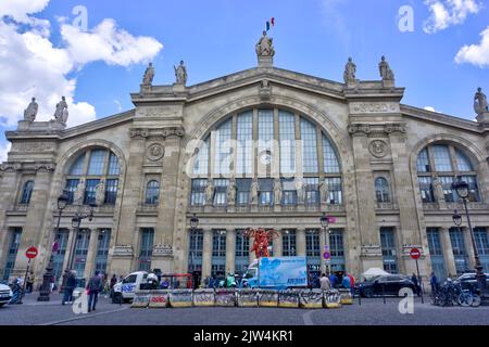 Paris, France - May 30, 2022: Exterior of Gare du Nord rail station with motion blurred pedestrians, parked vehicles and delivery van in foreground Stock Photo