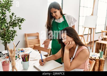 Two latin paint students arguing sitting on the table at art school. Stock Photo