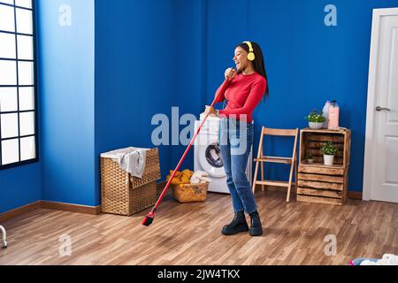 African american woman cleaning floor singing at laundry room Stock Photo