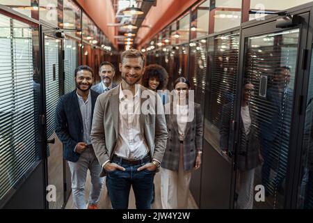 Group of happy, motivated business people standing together at office with their leader Stock Photo