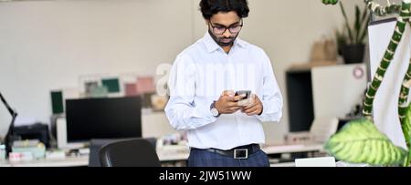 Elegant young indian business man using smartphone at work in office. Stock Photo