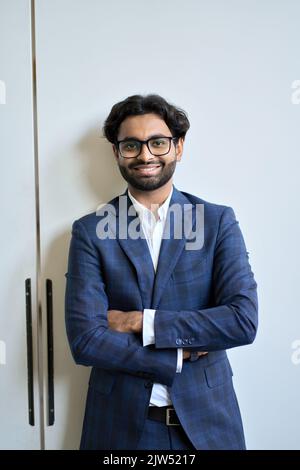 Smiling young indian business man wears suit in office, vertical portrait. Stock Photo