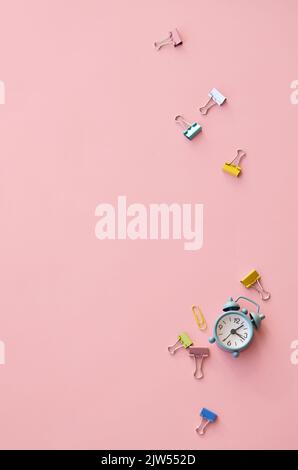 Small alarm clock and fasteners on pink background, flat lay, top view. Stock Photo