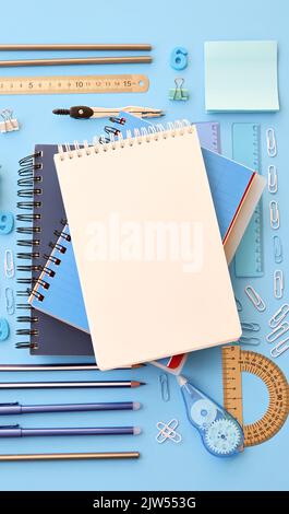 Stationery school supplies accessories on blue background, vertical flat lay. Stock Photo