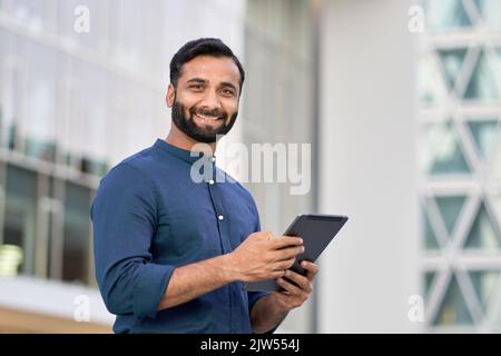 Smiling indian business man executive using digital tablet outdoors. Stock Photo