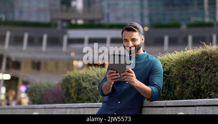 Professional indian business man using digital tablet in night city park. Stock Photo