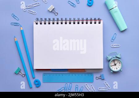 School stationery and open notebook on pastel lavender background, flatlay. Stock Photo