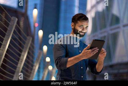 Rich successful indian business man standing using digital tablet in night city. Stock Photo