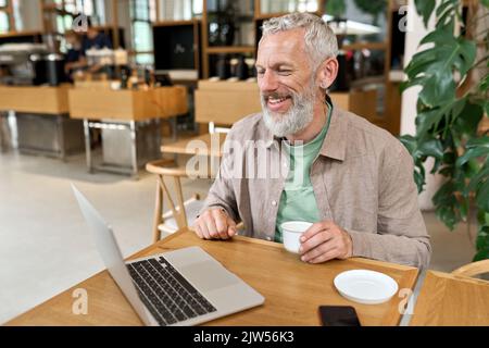 Happy older business man using laptop remote working or virtual learning. Stock Photo