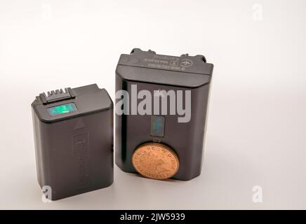 close-up of two different size Sony digital camera lithium ion batteries, NP-Fw50 and NP-FZ100 with a copper penny for size comparison Stock Photo
