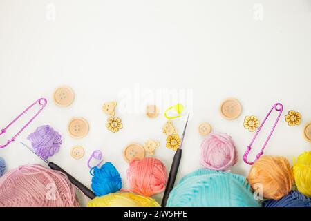 Flat lay composition with knitting threads and hook and buttons on white table, space for text, top view. Stock Photo