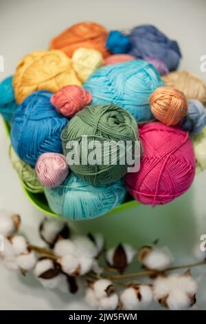 Multi-colored bright yarn lies in a box on a white table, selective focus. Stock Photo