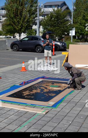 An artist adding coloured inserts to her very large woodblock at a Steveston demonstration in British Columbia Canada Stock Photo