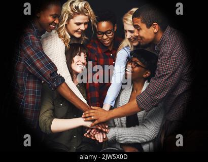 One for all. a group of cheerful work colleagues forming a huddle together. Stock Photo