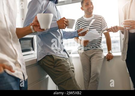 Group of diverse coworkers drink coffee during break and talking about work project Stock Photo