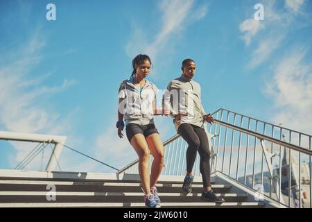 When the going gets tough...a young sporty couple running down a staircase. Stock Photo
