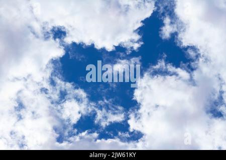 Cumulus flat or cumulus humilis clouds in blue sky, view from below.Abstract natural background of bright warm sky, selective focus. Vacation freedom Stock Photo