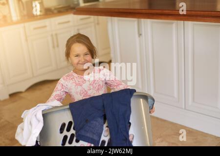 Im helping with housework. Portrait of a young girl holding a basket of laundry. Stock Photo
