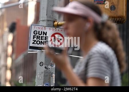 New York, USA. 03rd Sep, 2022. A woman walks past a “Gun Free Zone” sign attached to a traffic light pole on the corner of 46th Street and Sixth Avenue, one block south of Times Square, New York, NY, September 3, 2022. After U.S. the Supreme Court lifted the firearms concealed-carry restrictions, New York City has put up signs designating Times Square as a Gun Free Zone after passing legislation to ban firearms in the densely crowded and tourist area, which also includes subway, buses and (Photo by Anthony Behar/Sipa USA) Credit: Sipa USA/Alamy Live News Stock Photo