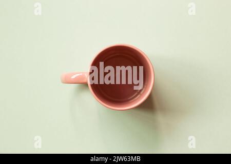 Pink mug cup on green background. copy space Stock Photo