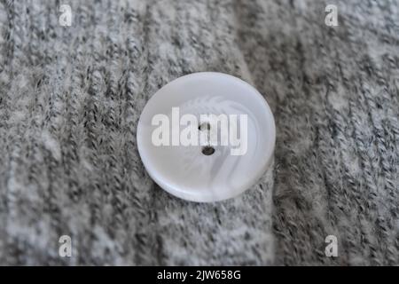 White plastic button on gray knitted fabric texture background Stock Photo