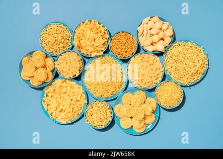 Above view with a large variety of pasta on blue plates, on a blue table. Various types of uncooked pasta in bright light, top view on a blue backgrou Stock Photo