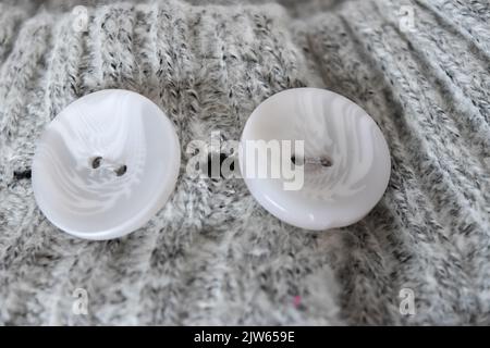 White plastic button on gray knitted fabric texture background Stock Photo
