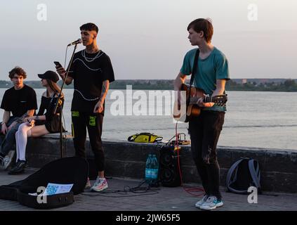 Boy electric guitar playing for people. Males on musical instruments in city promenade.Street musicians entertain citizens,selective focus.Teenage boy Stock Photo