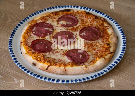 Salami Pizza Italian Style on a Round Plate Stock Photo