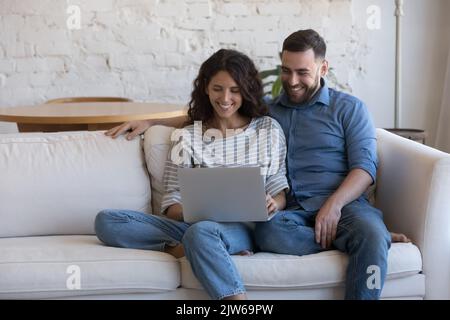 Couple sit on sofa with laptop do e-hopping at home Stock Photo