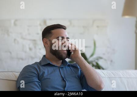 Happy millennial man talks on smartphone at home Stock Photo