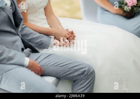 Bride and Groom holding hands during their wedding ceremony Stock Photo