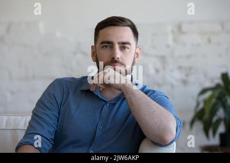 Man sit on couch in living room staring at camera Stock Photo