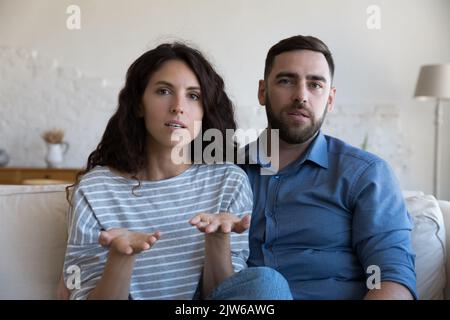 Serious couple look at camera having videocall conversation Stock Photo