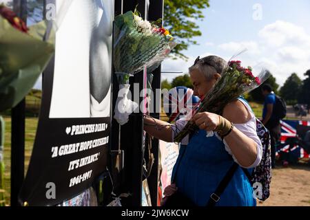 London, UK. 31st Aug, 2022. A woman plants flowers outside the gates of Kensington Palace in London. Mass tributes of the late Princess Diana adorn the gates of Kensington Palace as well wishers mark the 25th anniversary of the Royal's death in a Paris car crash. Credit: SOPA Images Limited/Alamy Live News Stock Photo