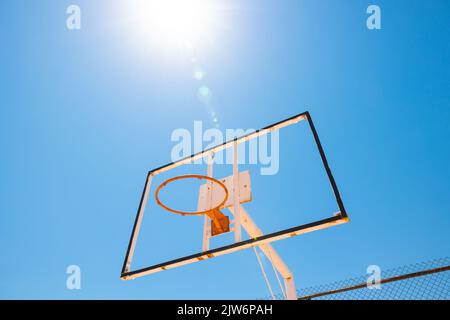 Broken backboard of basketball field in the park. Abandoned town concept photo. Sunlight and lensflare. Stock Photo