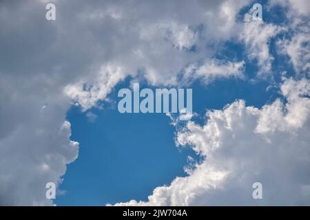 Beautiful cloudy sky. Frame made of clouds. Blue sky with lots of white fluffy cumulus clouds, natural background, full frame. Selective focus. Stock Photo