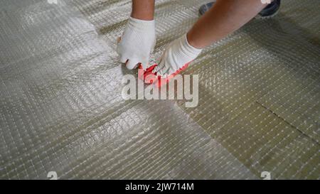 Laying a film on waterproofing on the floor. The master installs a film underfloor heating in the room. Installation of a warm floor. Floor soundproof Stock Photo