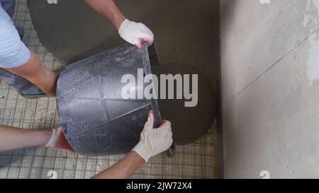 Workers pour the floor in the room with a mortar mixture. Self-leveling floor. Floor repair, liquid mixture, leveling flooring. Construction workers p Stock Photo