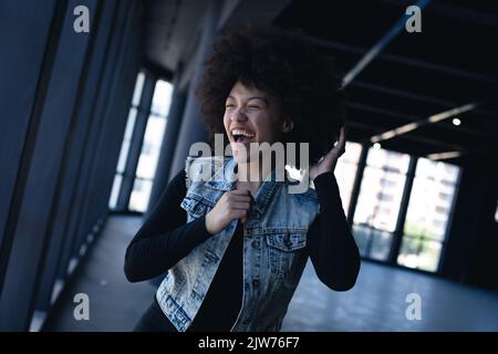 Mixed race woman laughing and dancing in an empty building Stock Photo