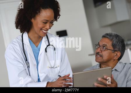 Senior mixed race man with female doctor home visiting talking using tablet Stock Photo