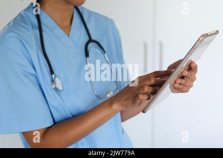 Close up of mixed race female doctor home visiting using tablet Stock Photo