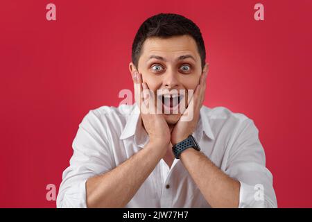 surprised young brunette man in white shirt Stock Photo
