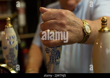 Close up of male hands pulling a pint at bar pump in an old english pub The Cockpit in the City of London , United Kingdom. Stock Photo