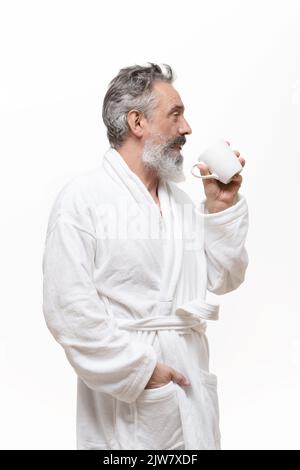 older man with beard in bathrobe holding a cup of coffee on with background Stock Photo