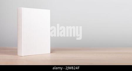 Banner with book mockup standing at wooden table. Novel, encyclopedia, code template with empty cover. Reading leisure, education, learning new inform Stock Photo